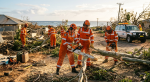 Queensland SES volunteers in orange uniforms clearing cyclone debris with chainsaws
